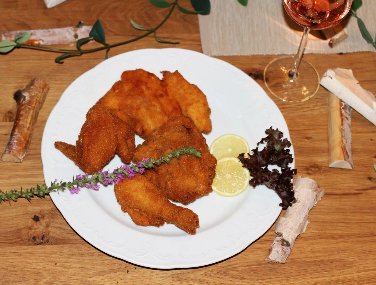Backhendl auf weißem Teller mit Zitrone und Blattsalat