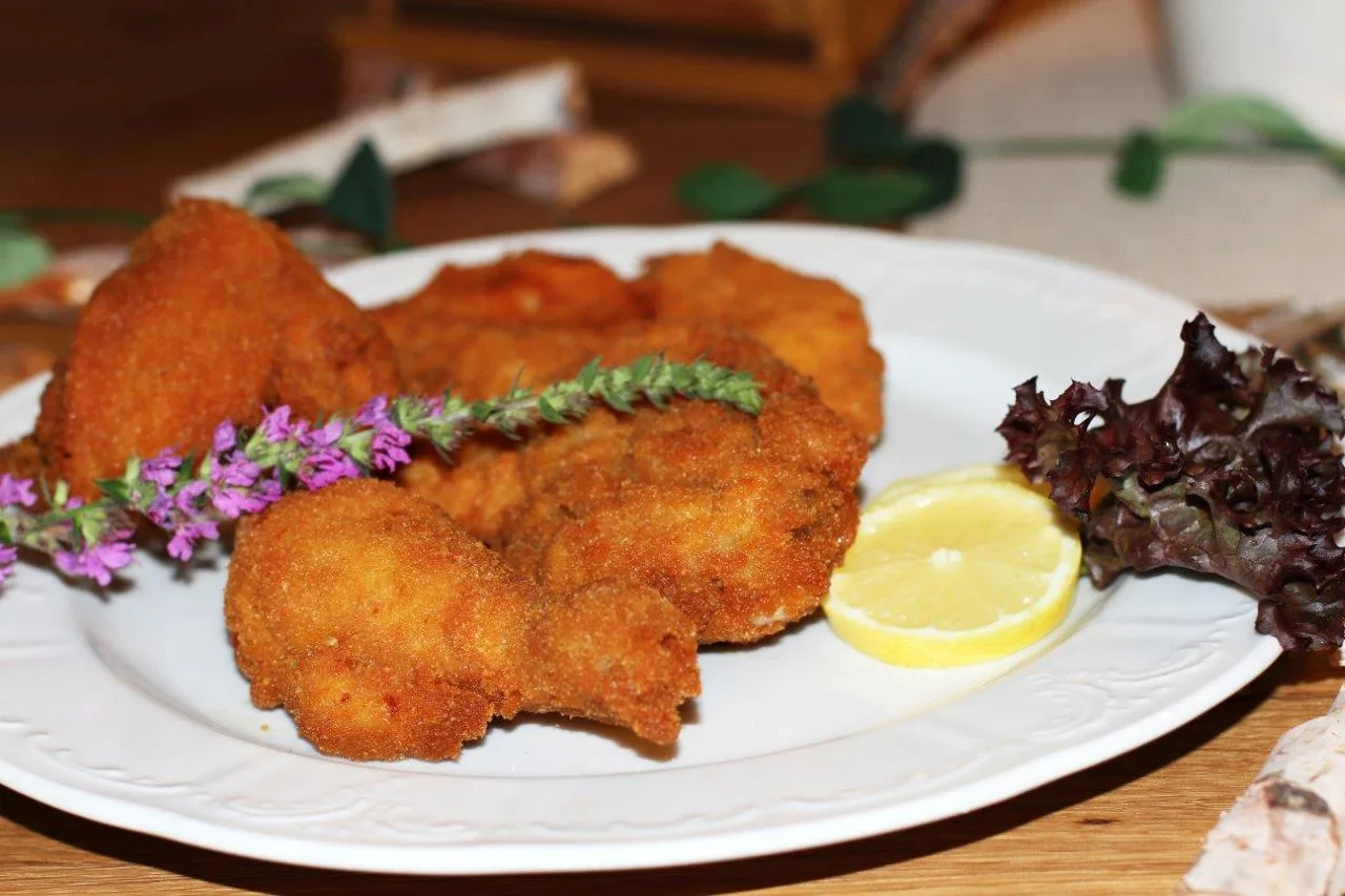 Backhendl mit Zitrone und Salatgarnitur auf einem Porzellanteller