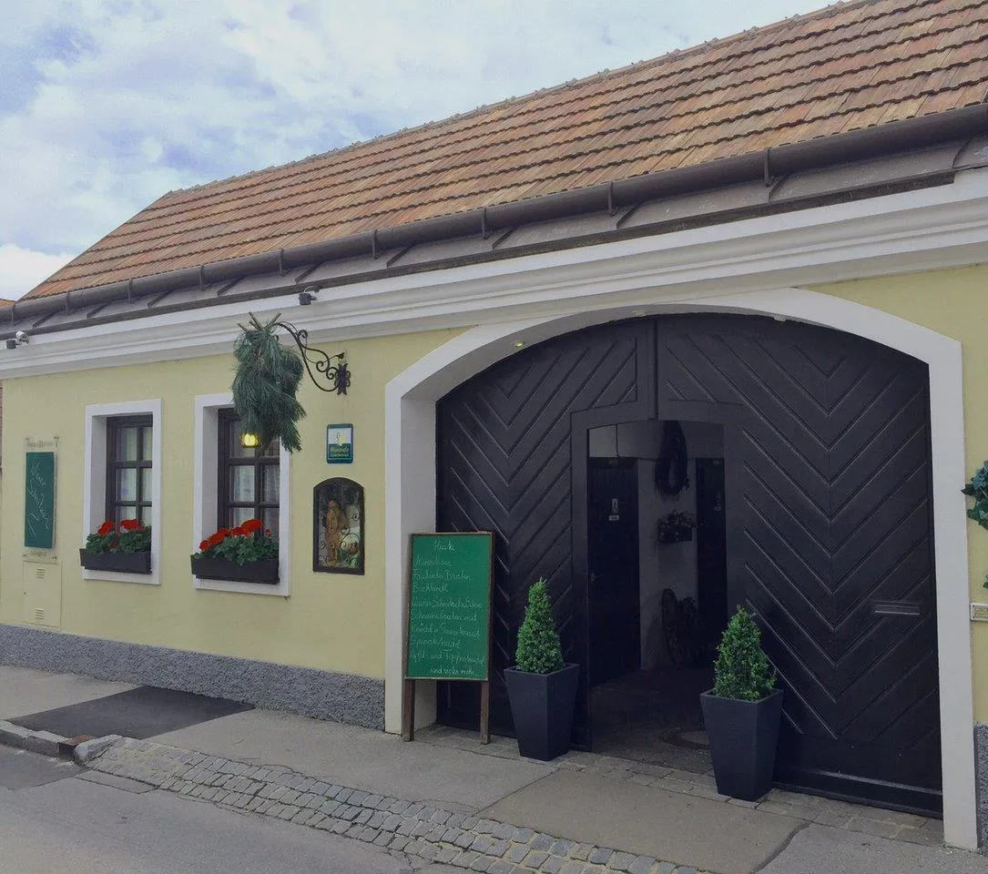 Straßenseite des Hauses in der Agnesstraße mit dem dunklen Rundbogentor und der Tafel mit den Speisen des Tages