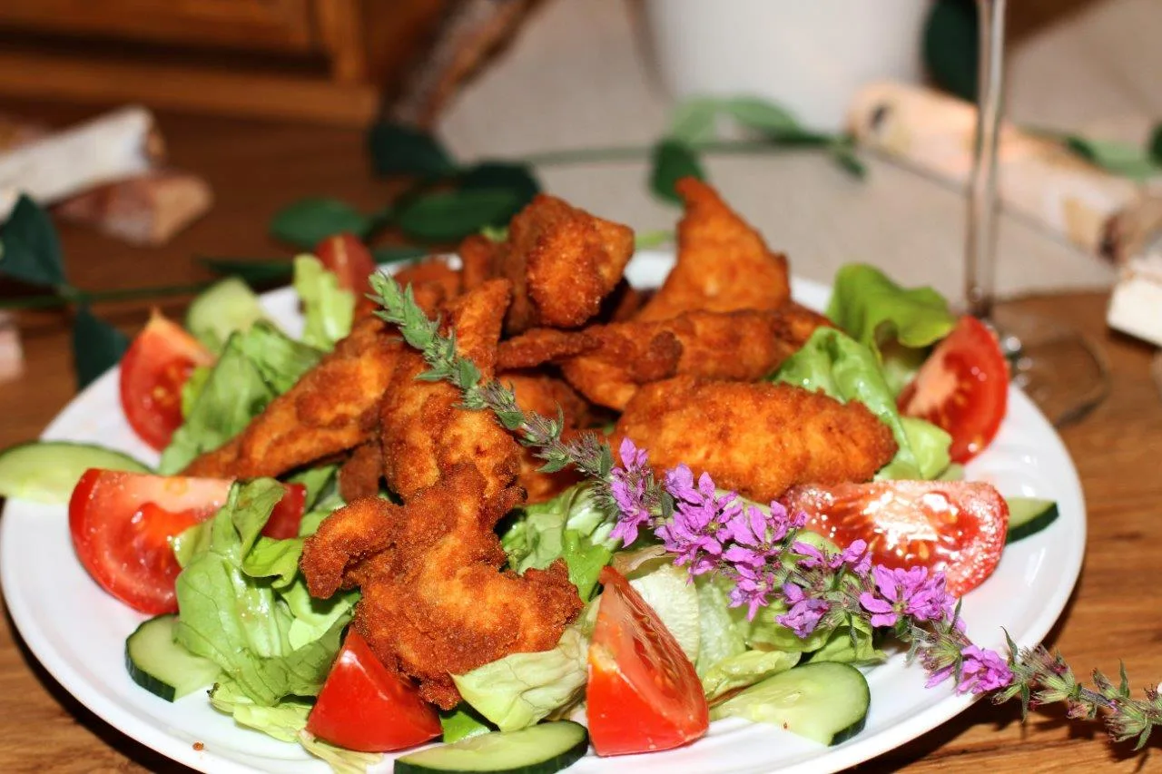 Gebackene Hühnerfiletstreifen auf Blattsalat mit Tomaten