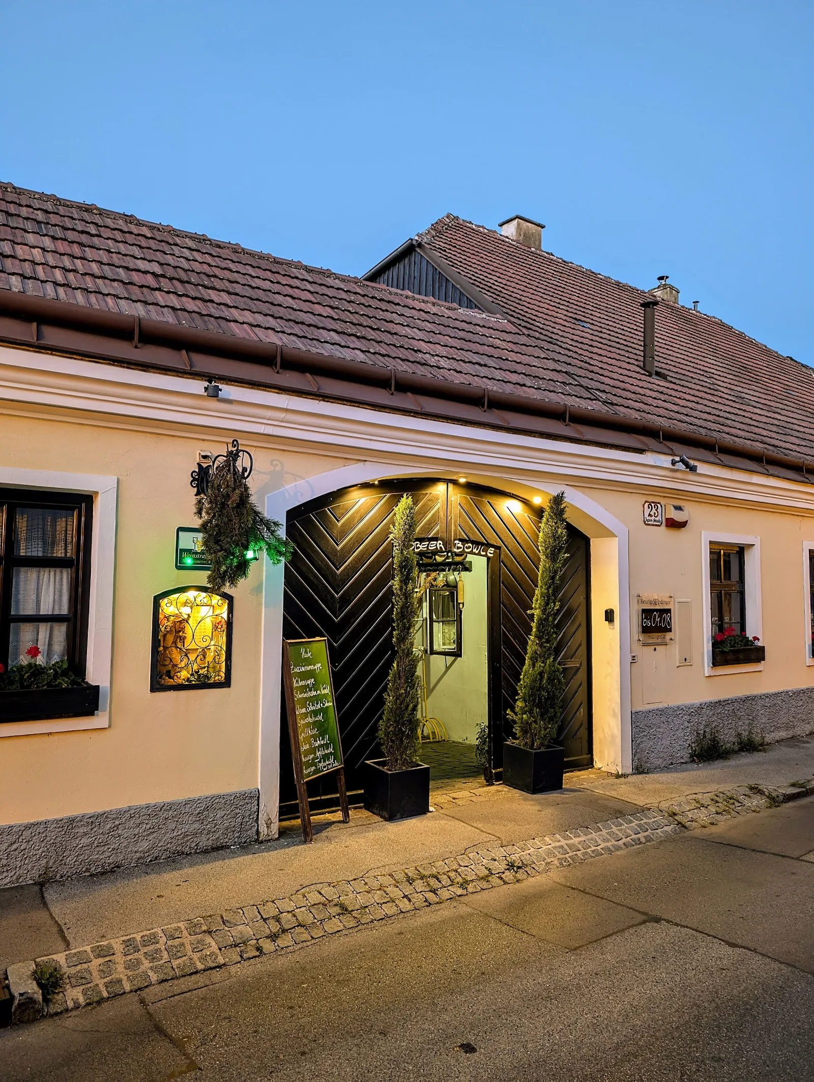 Hausfront in der Dämmerung, das Tor zum Hof ist beleuchtet